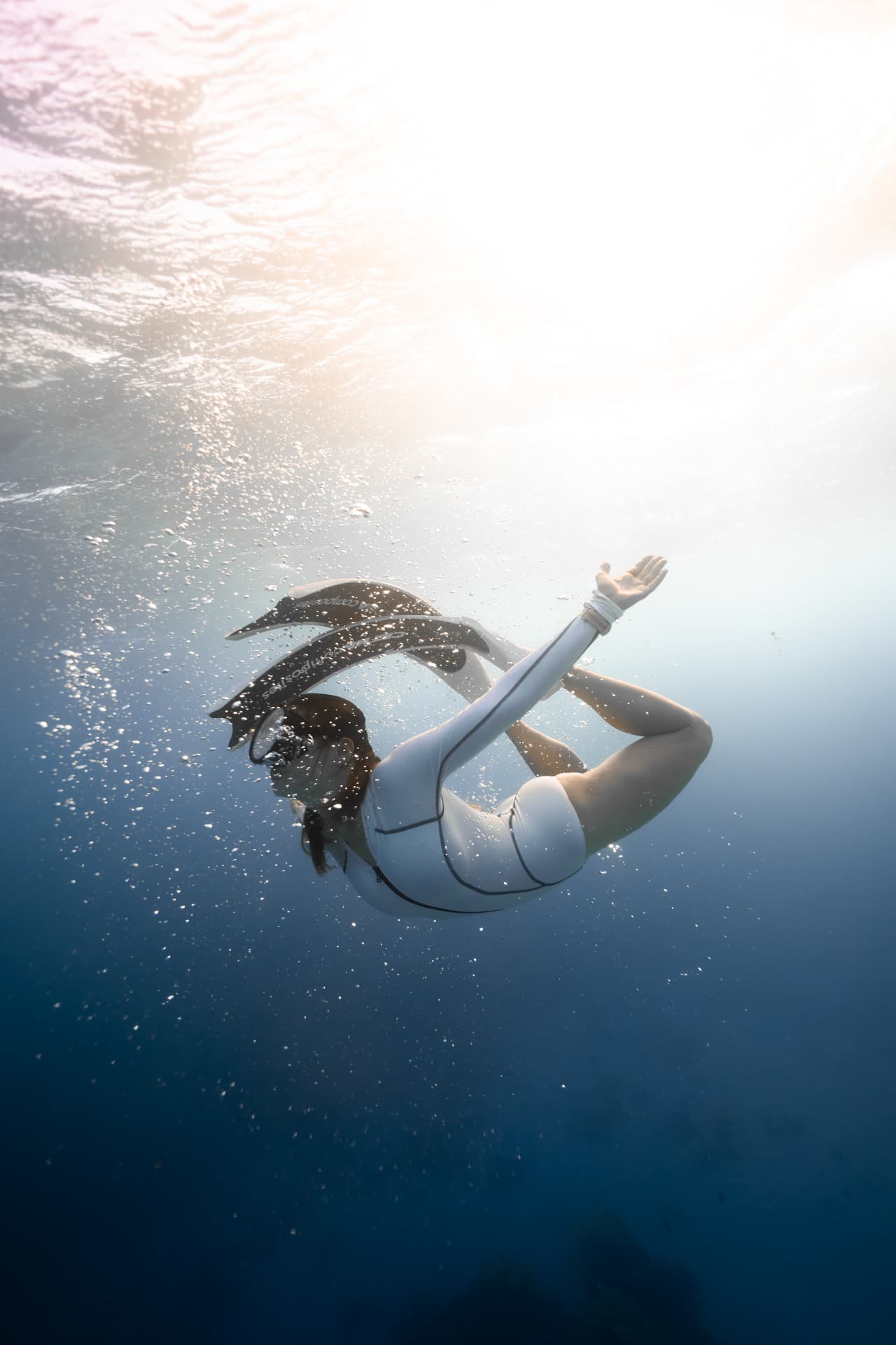 Claudia onder water in freediving-houding, omringd door rustig blauw licht