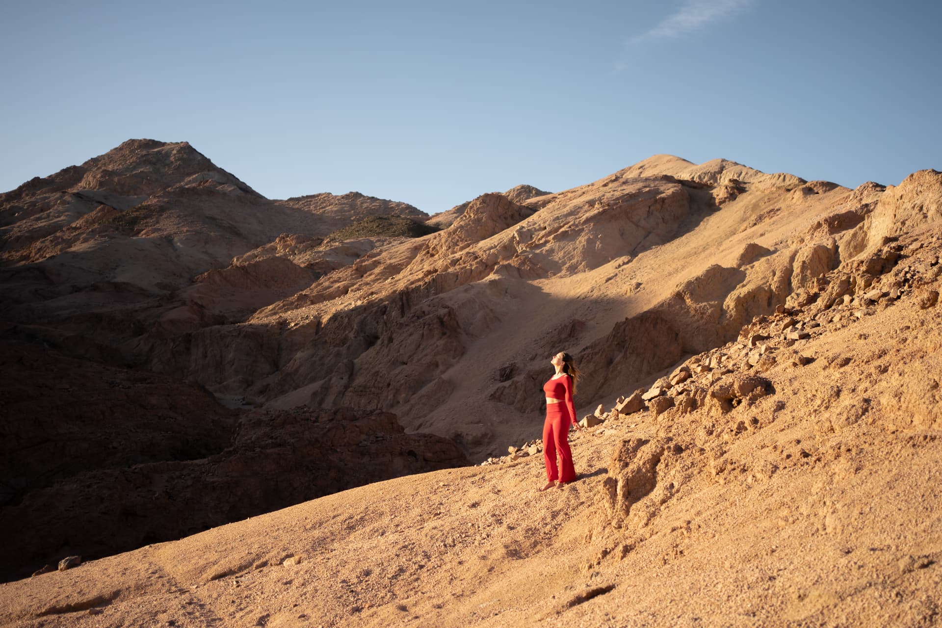 Claudia staat in een woestijnlandschap en kijkt omhoog naar de zon